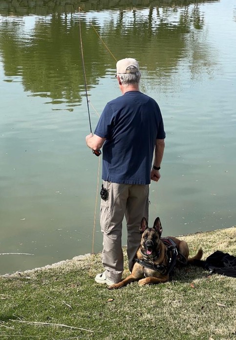 Marshall resting beside Jeff Daley while Jeff fishes